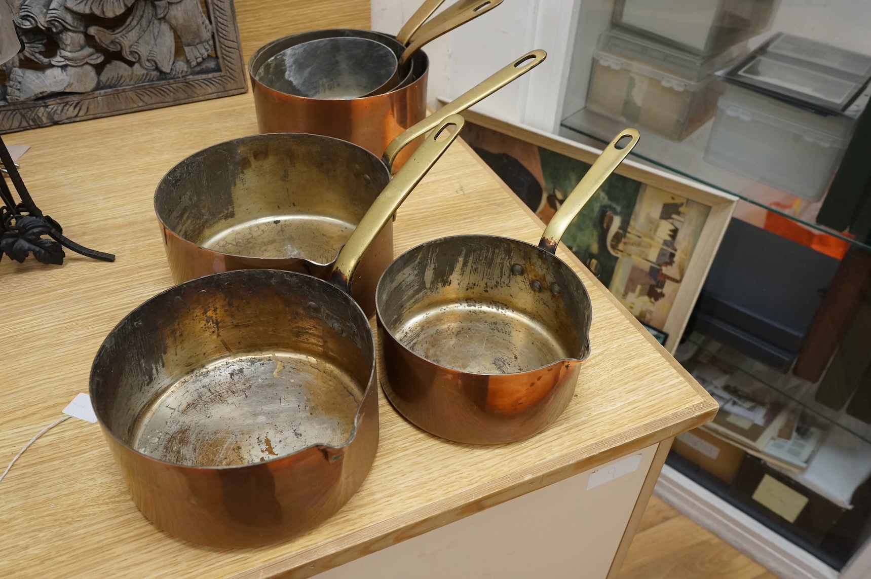 A set of three graduated copper and brass handled Saucepans and a similar set with pouring lid, largest 40cm in length